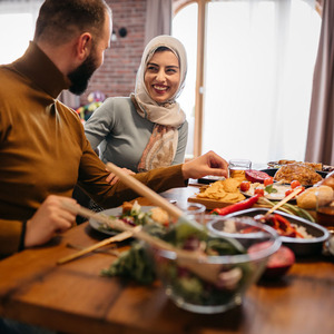 Happy Middle Eastern woman having Ramadan Iftar meal with her family at dining table